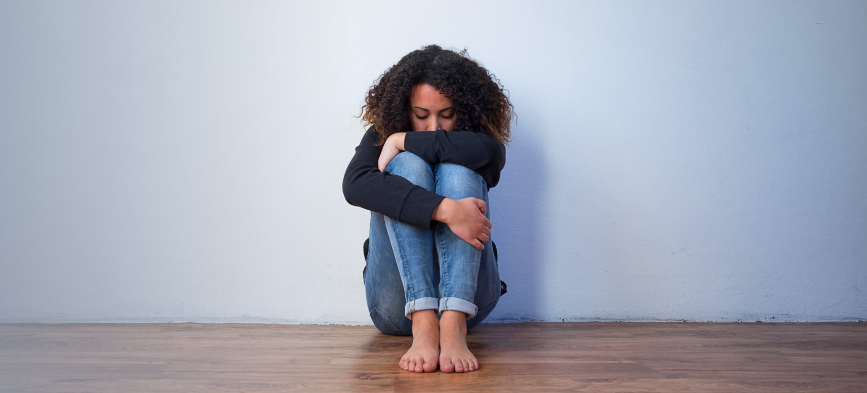 Sad adult woman sitting on the wooden floor